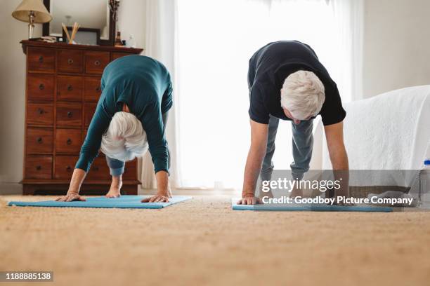 aktives seniorenpaar macht gemeinsam yoga in ihrem schlafzimmer - senior yoga stock-fotos und bilder