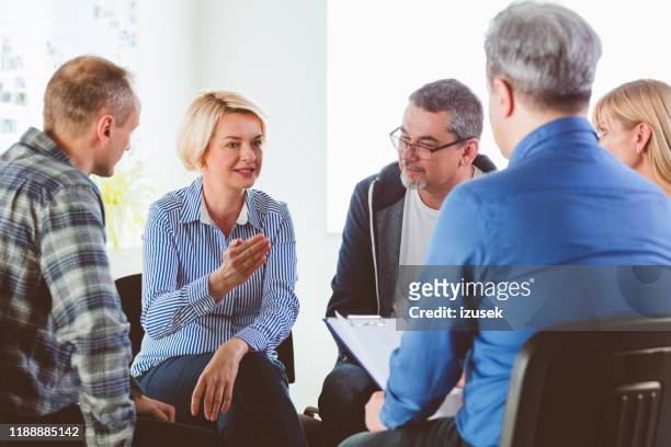 blond mature woman sharing issues during meeting - small group of people stock pictures, royalty-free photos & images