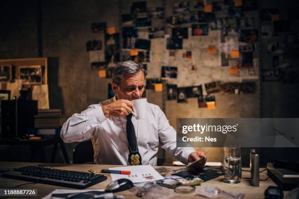 an old detective is looking at photos of suspects in his office - male police officer stock pictures, royalty-free photos & images