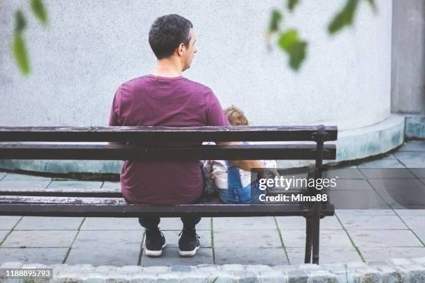 vater und sein kind sitzen auf der bank - bank müde frühling stock-fotos und bilder