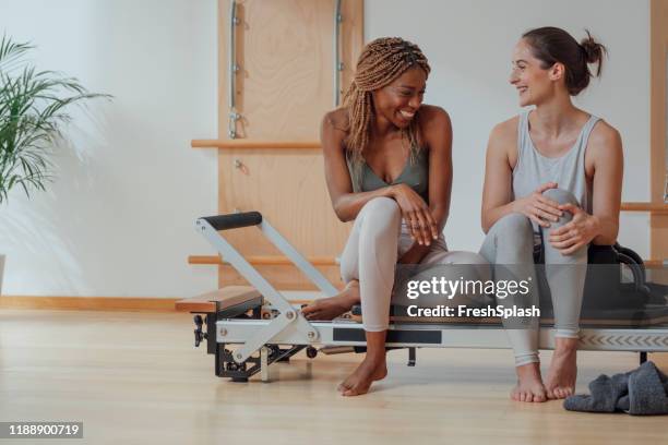 two women sitting on piiates reformer - reformer stock pictures, royalty-free photos & images