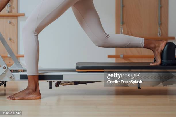 woman doing pilates exercise on reformer - pilates abstract stock pictures, royalty-free photos & images