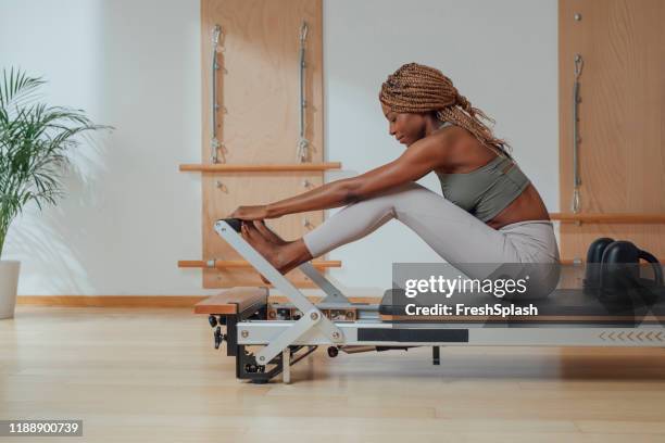 woman doing pilates exercise on reformer - pilates equipment stock pictures, royalty-free photos & images