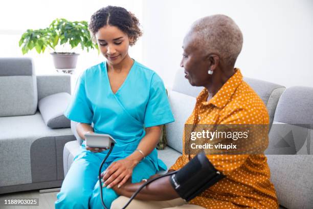 nurse measuring patient's blood pressure - hospice stock pictures, royalty-free photos & images