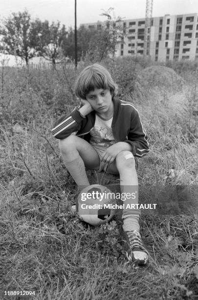 Jeune garçon avec un ballon de footbal dans un terrain vague en banlieue parisienne en juin 1974, France.