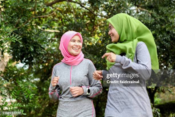 two muslim women runner running together - malay people stock pictures, royalty-free photos & images