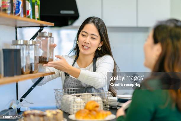 コーヒー豆を説明する若い女性カフェのオーナー - customer satisfaction ストックフォトと画像