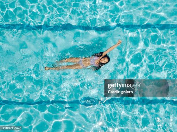 drone view on teenage girl in swimming pool - backstroke stock pictures, royalty-free photos & images