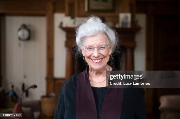 portrait of a beautiful senior woman in living room - hair bun scarf woman stock pictures, royalty-free photos & images