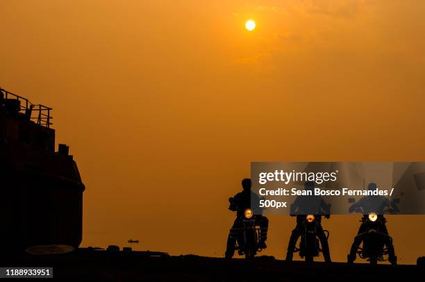 silhouettes of three bikers at sunrise,  mumbai, maharashtra, india - motorcycle group stock pictures, royalty-free photos & images