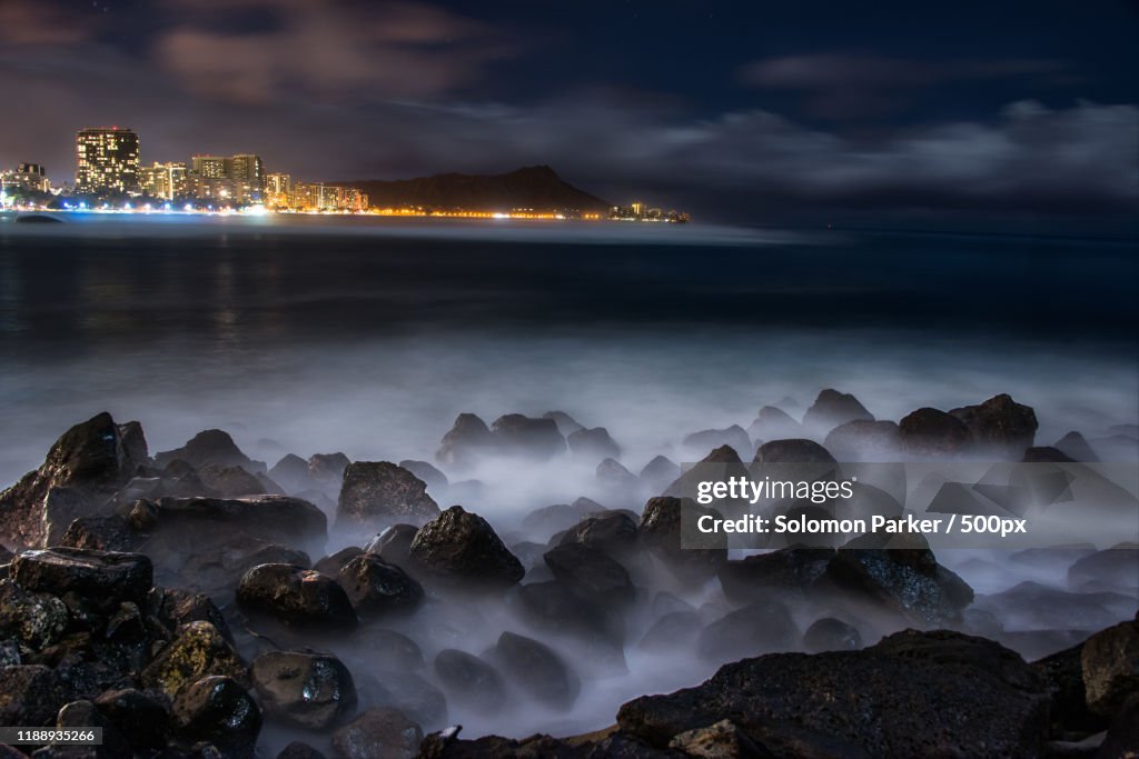 Illuminated city skyline over misty sea