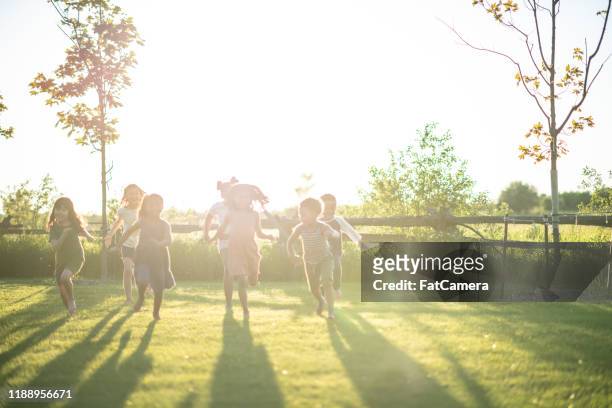 multi-ethnic group of children running in the sunlight stock photo - summer school imagens e fotografias de stock