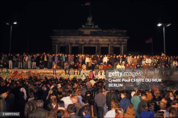 People stand on the Berlin Wall on November 10, 1989 in Berlin, Germany.
