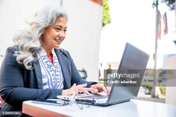 latina businesswoman usando laptop en cafe - disruptagingcollection fotografías e imágenes de stock