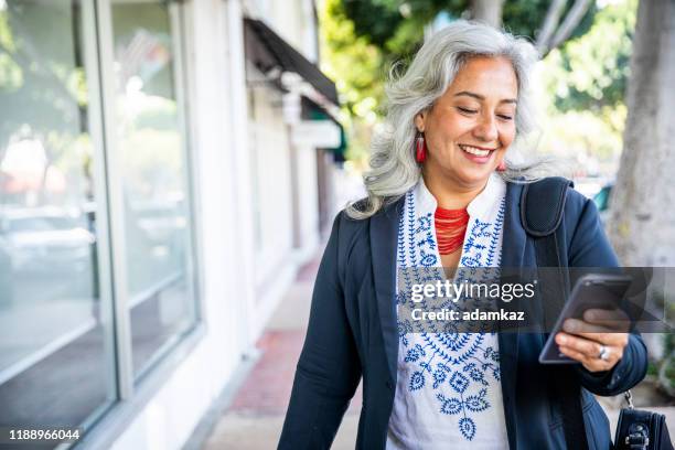 mexican businesswoman texting - mature adult on phone stock pictures, royalty-free photos & images