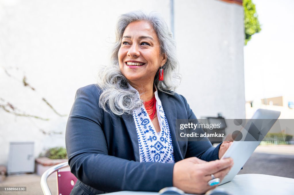 Femme d'affaires de Latina utilisant la tablette au café