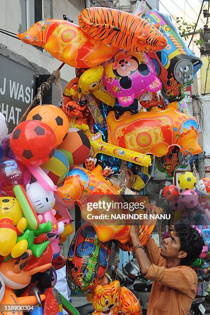 Indian student Dasraj 18, ties balloons to a stick to sell on the roadside in Amritsar on July 12, 2011. Dasraj sells balloons in the evening and...