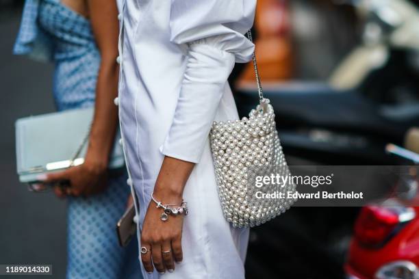 Guest wears a white dress with leg-of-mutton sleeves, a pearl woven beadwork bag, outside the Bottega Veneta show during Milan Fashion Week...