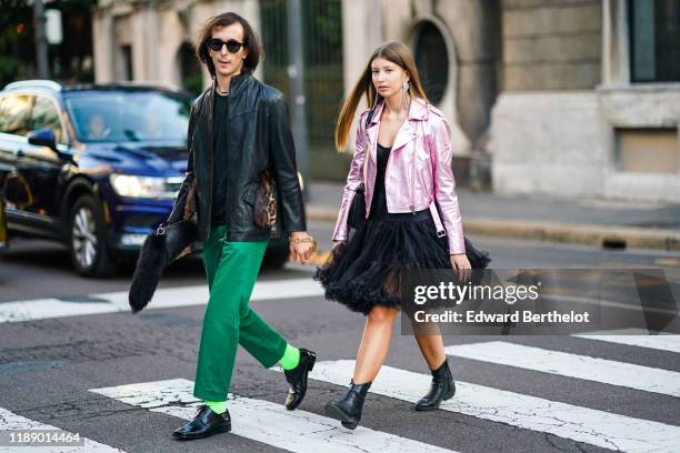 Guest wears sunglasses, a black leather jacket with a fluffy leopard print belt, a bracelet, emerald-green pants ; A guest wears earrings, a shiny...