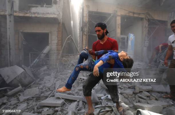 In this file photo taken on May 26 a man evacuates a young bombing casualty after a reported air strike by regime forces and their allies in the...