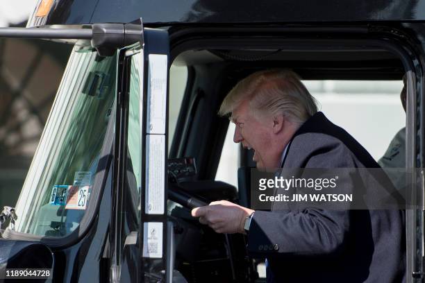 In this file photo taken on March 23, 2017 US President Donald Trump sits in the drivers seat of a semi-truck as he welcomes truckers and CEOs to the...