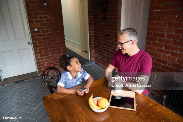 happy moment between dad and schoolgirl at dining table - melbourne school stock pictures, royalty-free photos & images