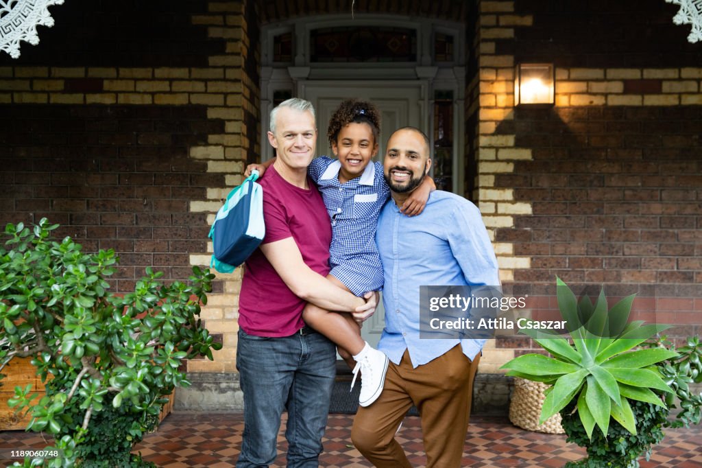 Portrait of fathers and daughter standing in front of house