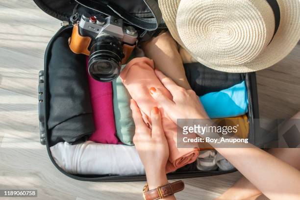 top view of tourist woman open suitcase for pack and arranging colorful cloths for travelling. - rolling stock-fotos und bilder