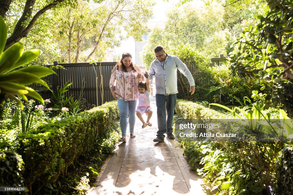 Mum and dad arriving home and lifting up little girl