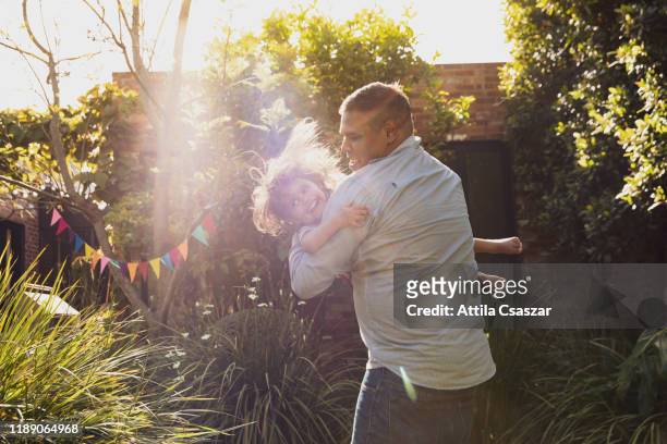 father and little daughter's happy jumping moments in garden - australia home stock-fotos und bilder