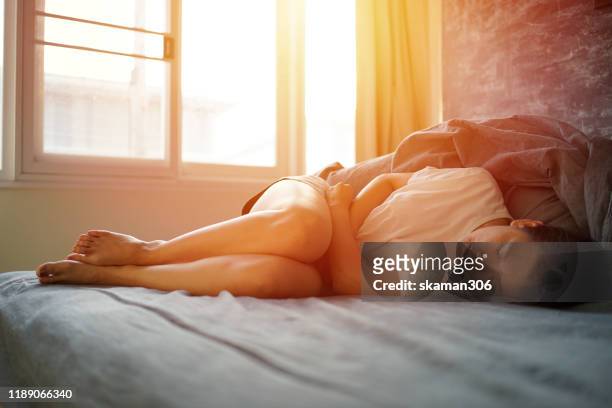 asian female feel hurt and pain on period on the bed - period blood stockfoto's en -beelden