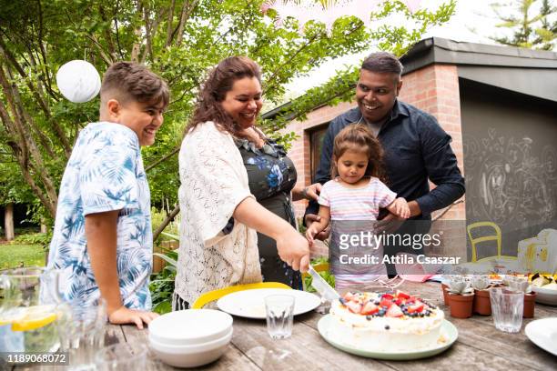 mother cutting cake for her birthday celebration with family - thisisaustralia stock-fotos und bilder
