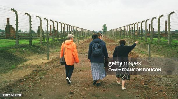 Des visiteurs parcourent l'allée centrale ceinturée de barbelés, le 08 août 2000 dans le camp d'extermination d'Auschwitz-Birkenau, lors d'un voyage...