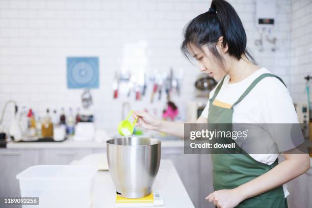 young asian female add milk for bake in kitchen - asian cooking stock-fotos und bilder