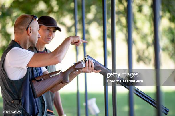 instructeur onderwijs volwassen vrouw skeet schieten en geweer handling - schietsport stockfoto's en -beelden