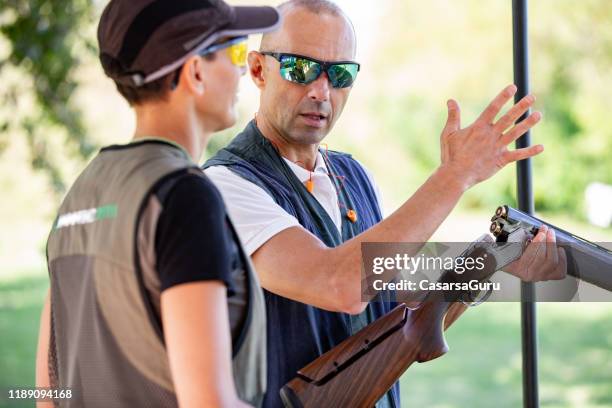 instructor teaching adult woman how to handle a shotgun - target shooting stock pictures, royalty-free photos & images