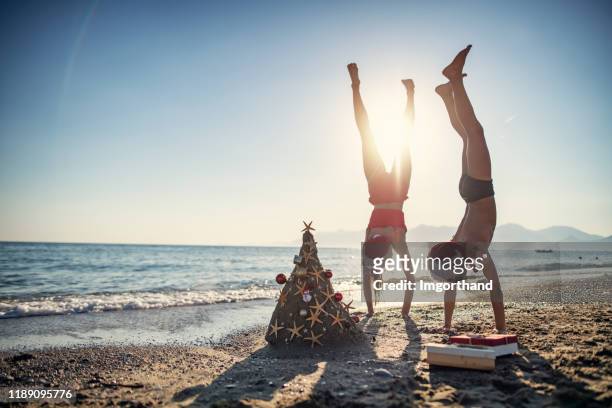 kids enjoying summer christmas - handstand beach stock pictures, royalty-free photos & images
