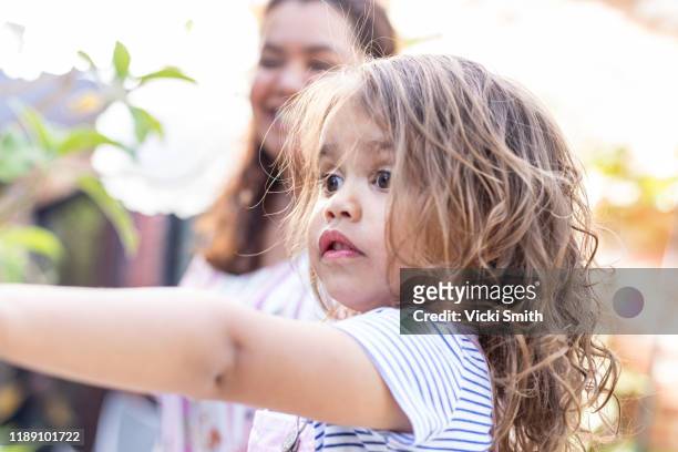 indigenous women standing behind young daughter who is pointing and smiling - aboriginal girl stock pictures, royalty-free photos & images