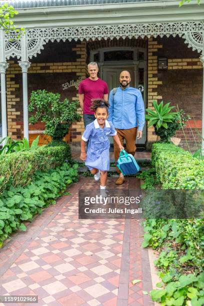 two fathers and a daughter outside ready for school - melbourne school stock-fotos und bilder