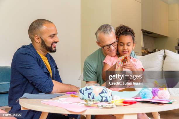 young girl makes a valentines card with her two fathers - home made gift stock pictures, royalty-free photos & images