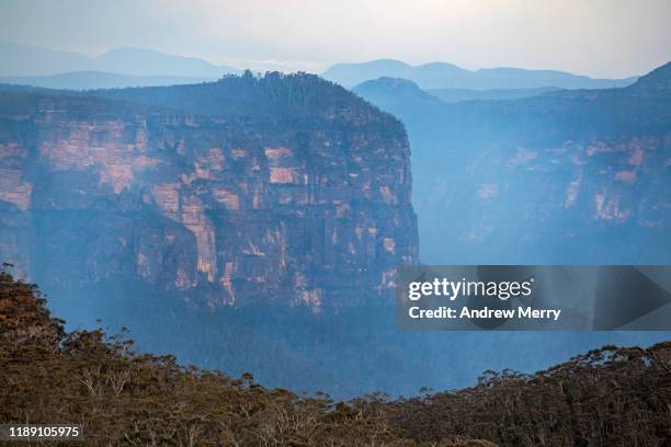 blue smoke from forest fire, bushfire in the grose valley with steep cliff face, escarpment at dusk, sunset, blue mountains, australia - brousse photos et images de collection