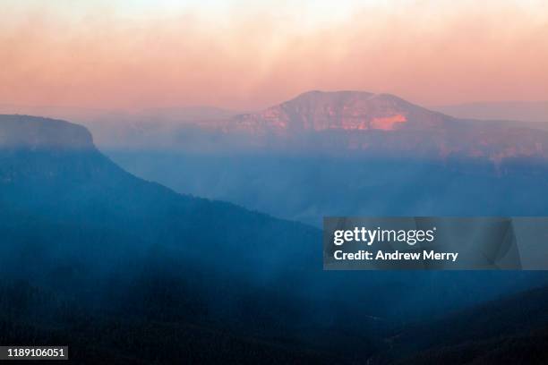 smoke from forest fire, bushfire in the grose valley with mount banks illuminated by sunlight at dusk, sunset, blue mountains, australia - blue mountain range stock pictures, royalty-free photos & images