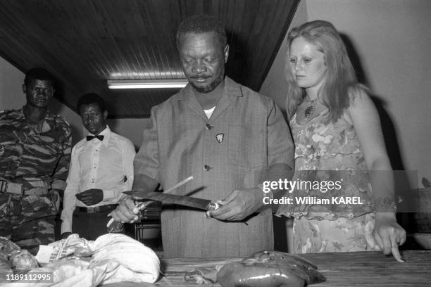 Jean-Bedel Bokassa aiguise un couteau en compagnie de sa femme Gabriella Drimbo lors d'une fête organisée après une partie de chasse dans le parc...