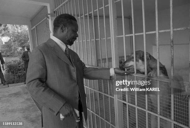 Jean-Bedel Bokassa donne à manger à l'un de ses chiens enfermé dans une cage dans la Villa Nasser à Bangui en mars 1975, République centrafricaine.