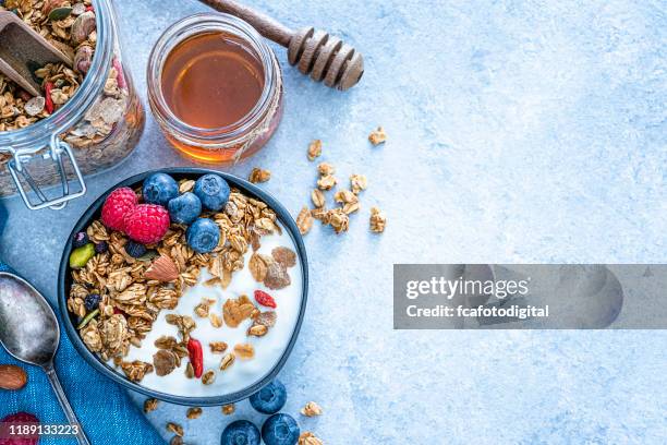 gesundes essen: hausgemachter joghurt und müsli von oben auf blauem tisch geschossen. kopierraum - granola stock-fotos und bilder