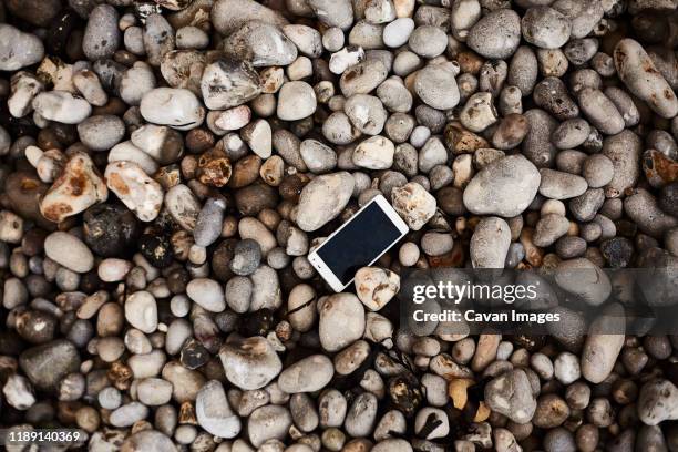 smartphone laying on the pebble shore - rubble stock pictures, royalty-free photos & images