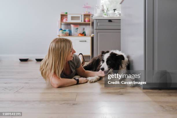 happy woman smiling while petting her dog at home - laminat stock-fotos und bilder