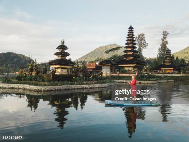 female sup surfer at bratan lake - pura ulu danau temple stock pictures, royalty-free photos & images