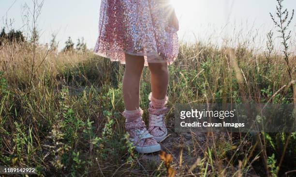 young girls feet and sparkly dress walking through grass at sunset - sweet little models stock pictures, royalty-free photos & images