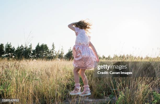 young girl dancing outside at sunset in a sparkly dress - children dancing outside stockfoto's en -beelden